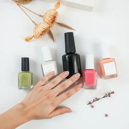 Non-toxic nail polish bottles and a hand with neatly manicured nails on a clean background