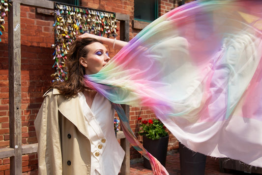 a woman is holding a colorful scarf in front of her face