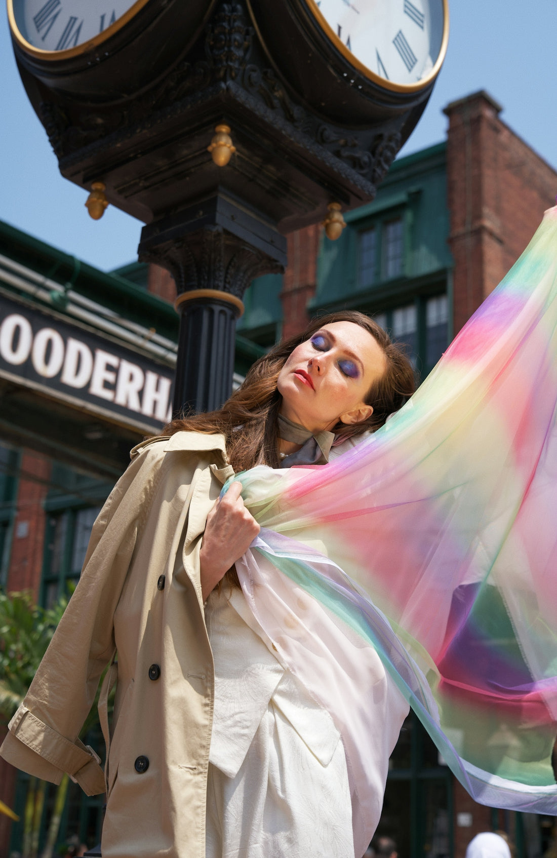a woman in a trench coat holding a colorful scarf