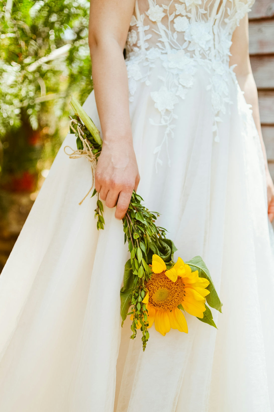 a woman in a wedding dress holding a bouquet of sunflowers