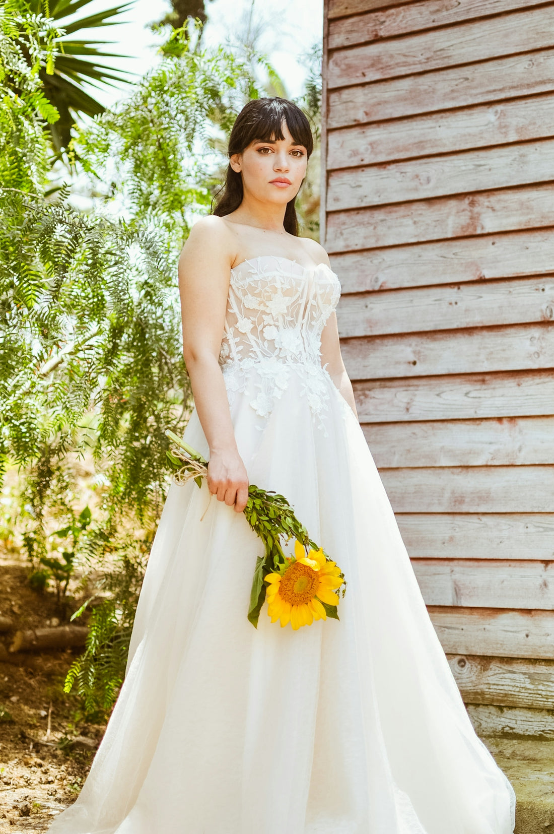 a woman in a wedding dress holding a bouquet of sunflowers