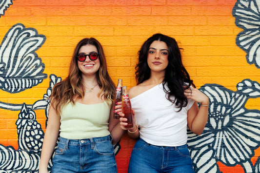 Two women standing next to each other in front of a wall