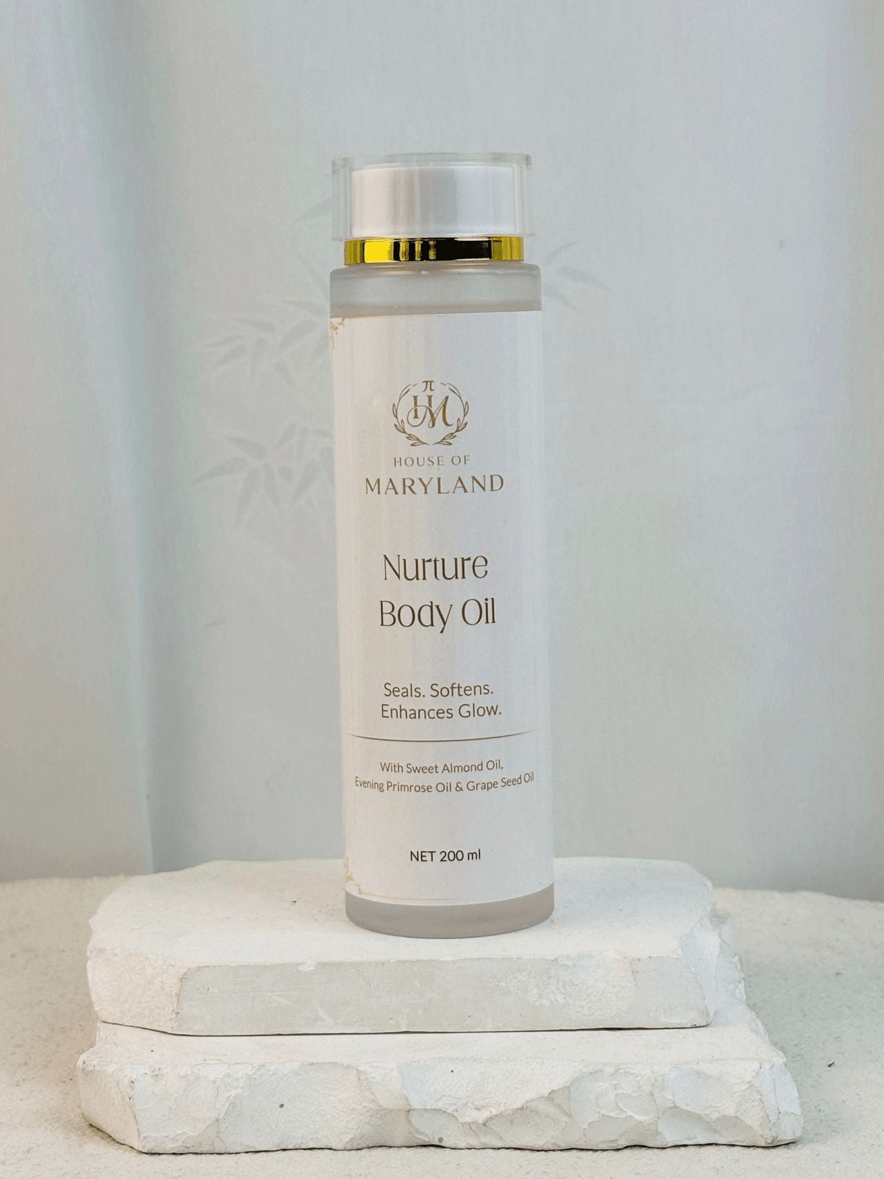 House of Maryland body oil bottle on pedestal, gold cap and white label, 200 ml